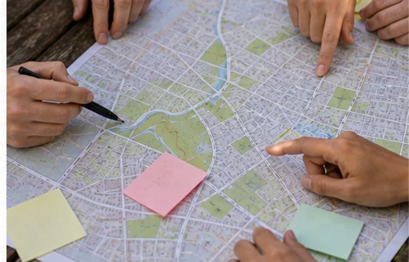Hands pointing at a neighborhood map with sticky notes